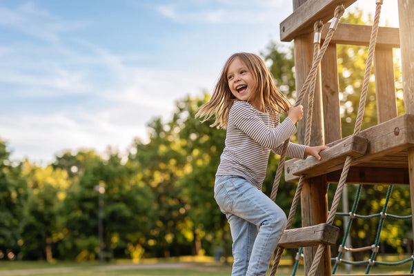 Kind klettert fröhlich auf dem Spielplatz